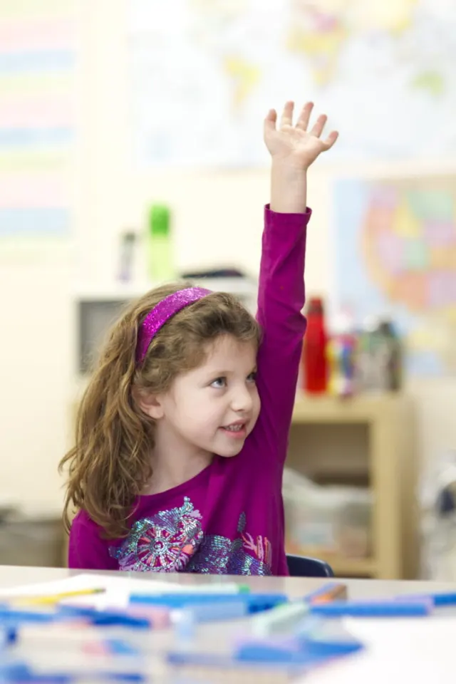A young student raising her hand in class